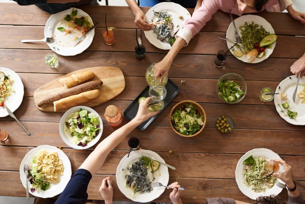 pexels photo 3184192 An overhead shot of a dining table featuring various pasta dishes and salads shared by a group.