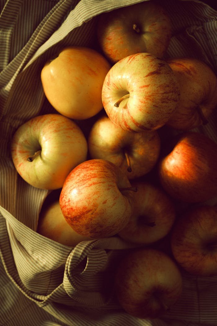 ours-journey A collection of fresh red apples in a rustic cloth bag, showcasing their vibrant and natural appeal.